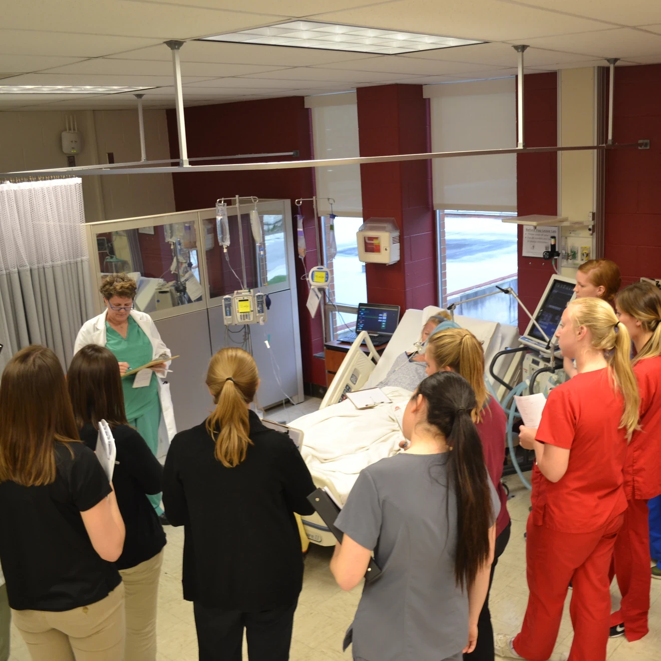 Health Care students in a circle around a patient bed