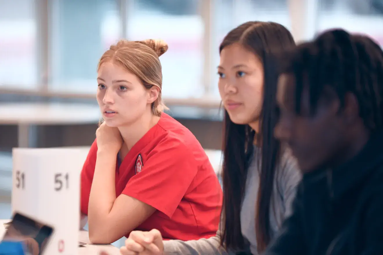 Three students seated at a table during a IPE teamwork event