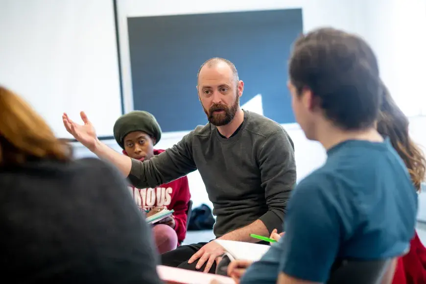 A professor speaking to students in a college classroom