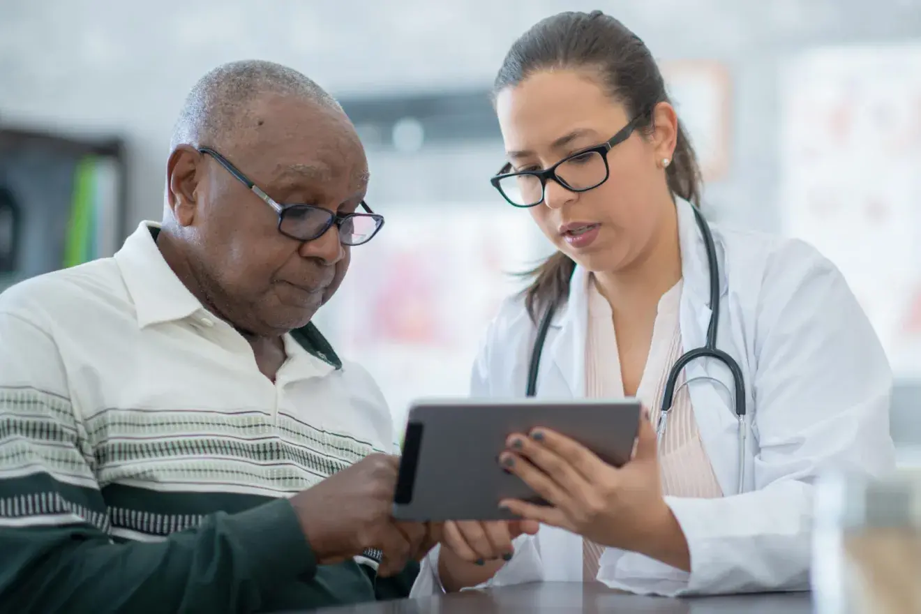 A young doctor assisting a patient use a tablet