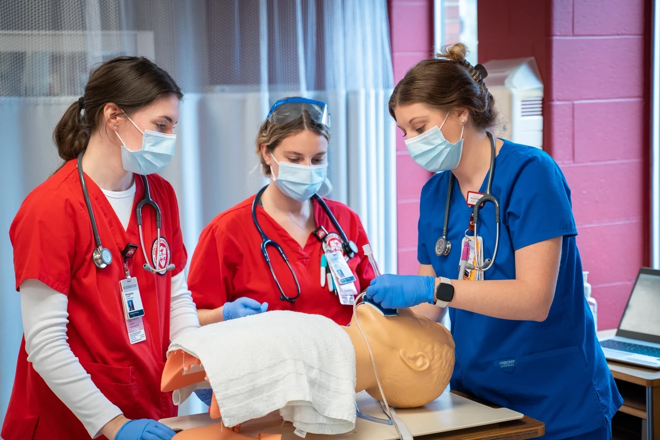 Three medical students learning on a medical manikins
