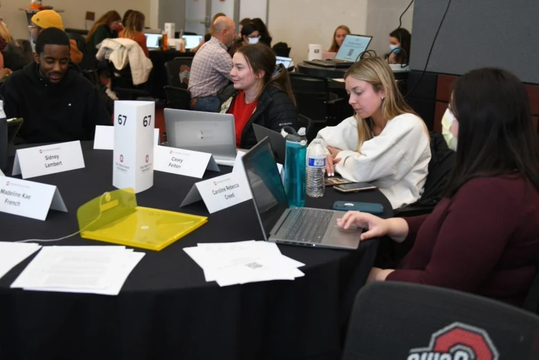 Students at a round table with laptops talking through a patient case