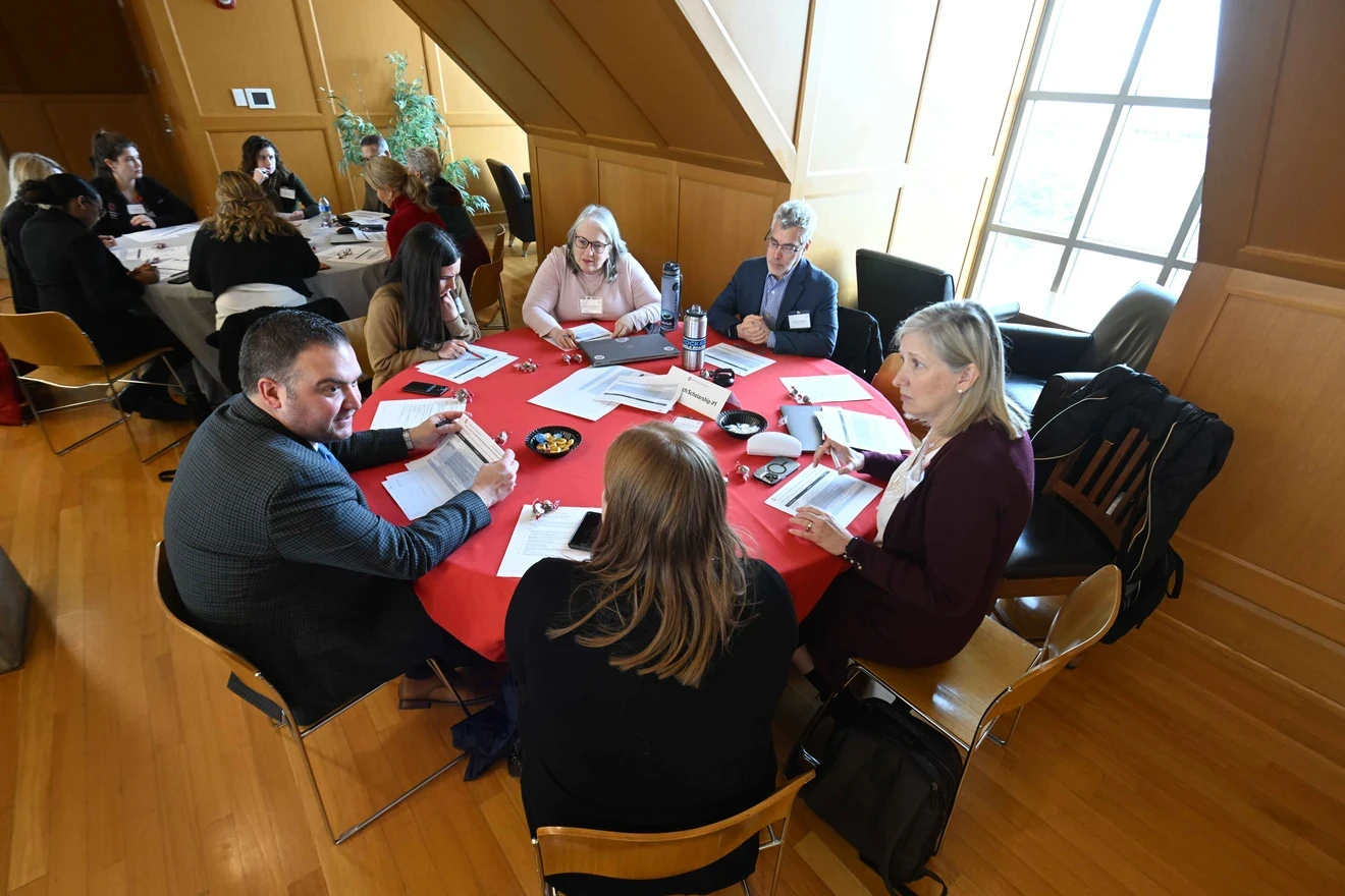 a team of colleagues discuss while gathered around a round table